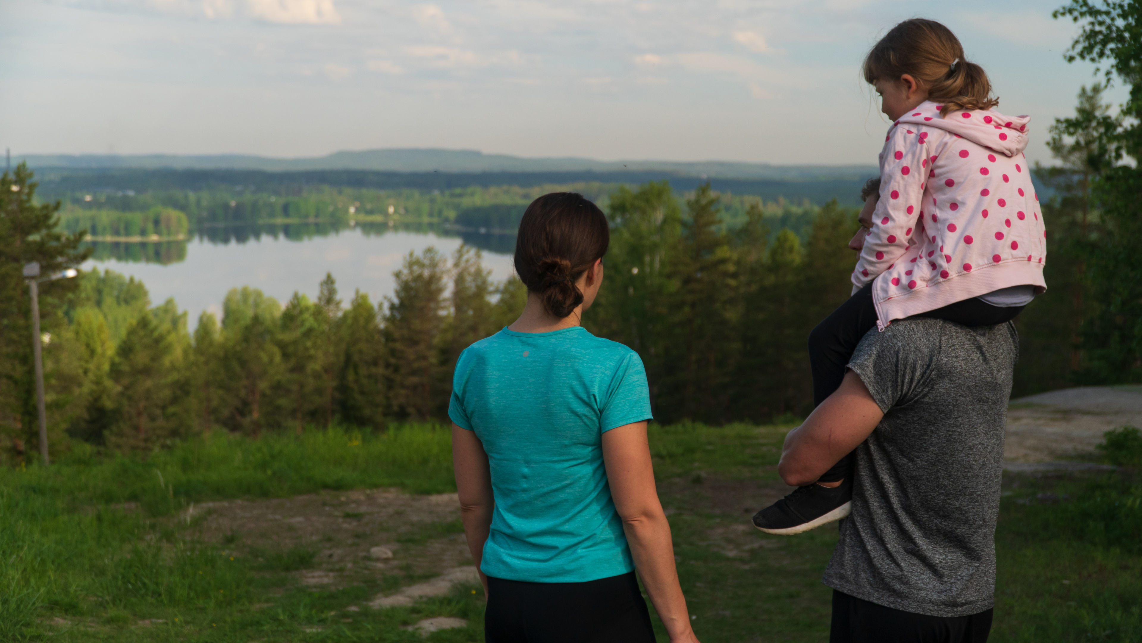 kolmen hengen perhe katsoo alas Paloisvuoren huipulta