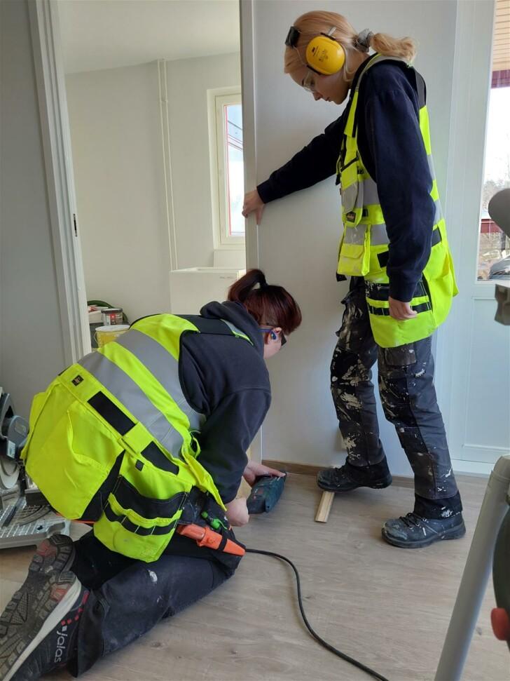 Kaksi Ysao:n opiskelijaa tekemässä remonttia asunnon oveen.