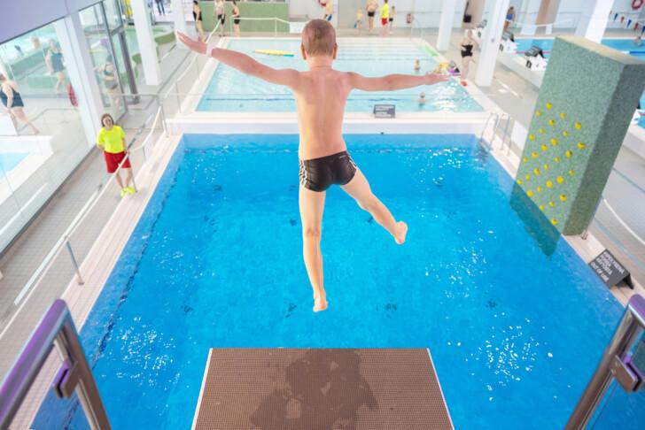 Lapsi hyppäämässä uimahallin hyppytornista Uimahalli Saukossa.