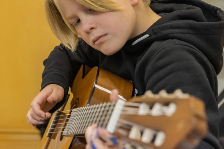 Lapsi soittamassa akustista kitaraa.